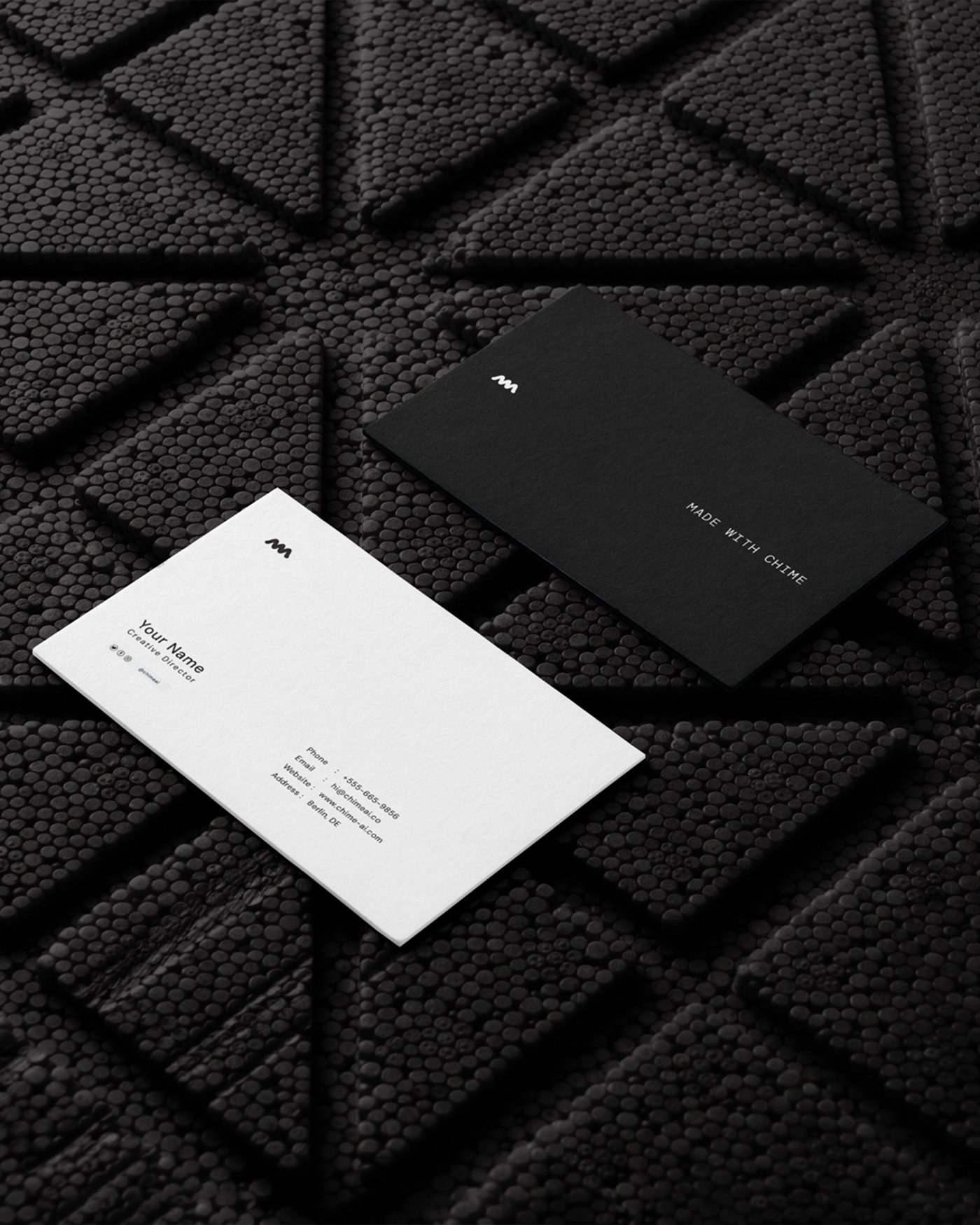 Business cards, one white and one black, on a dark textured surface
