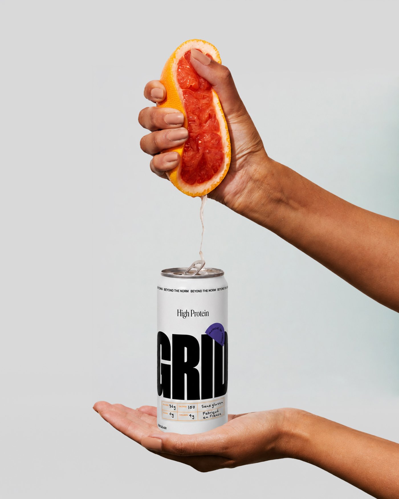 A hand squeezing a grapefruit over a Grit can