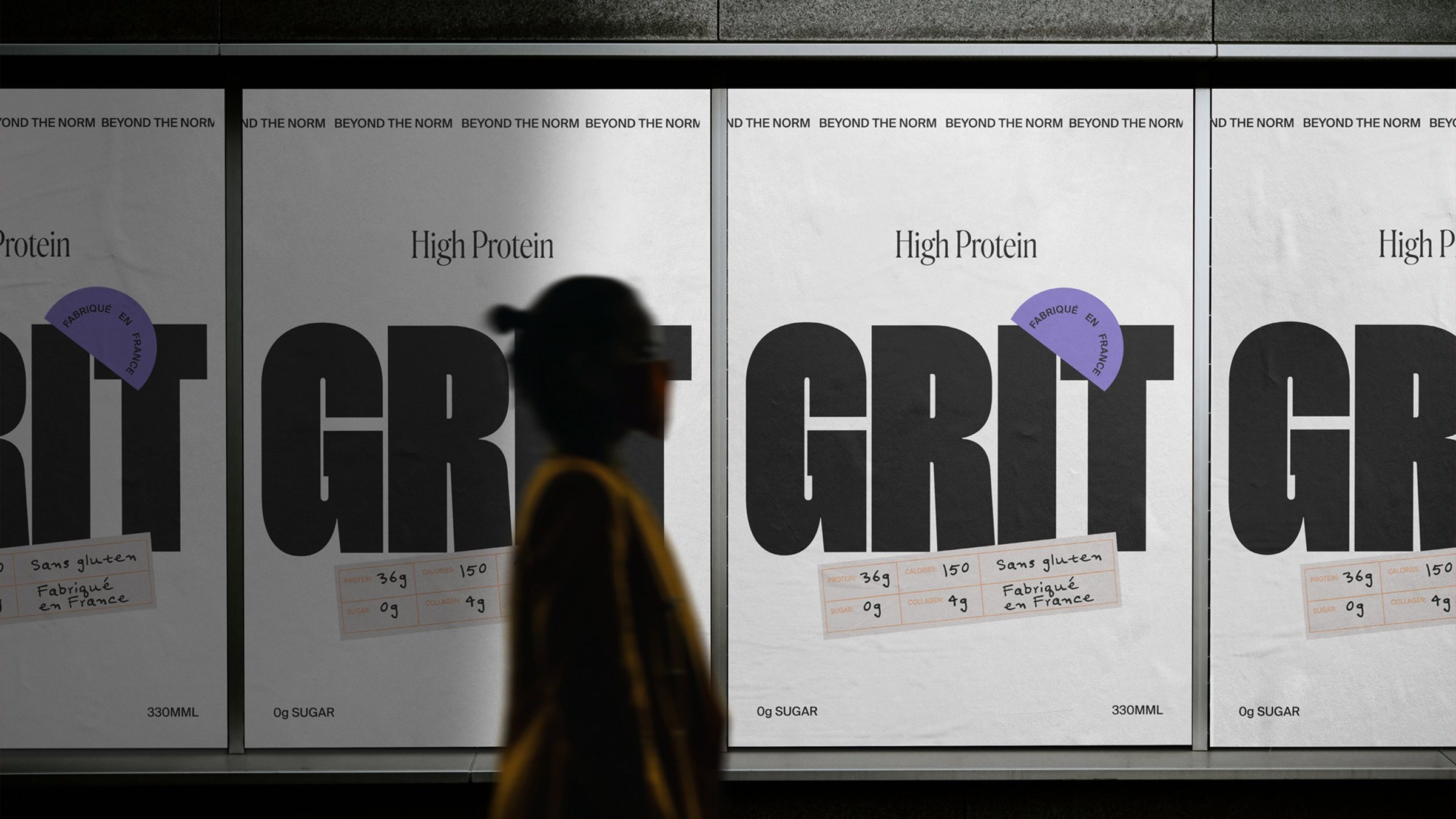 A row of backlit Grit posters in a transit passage