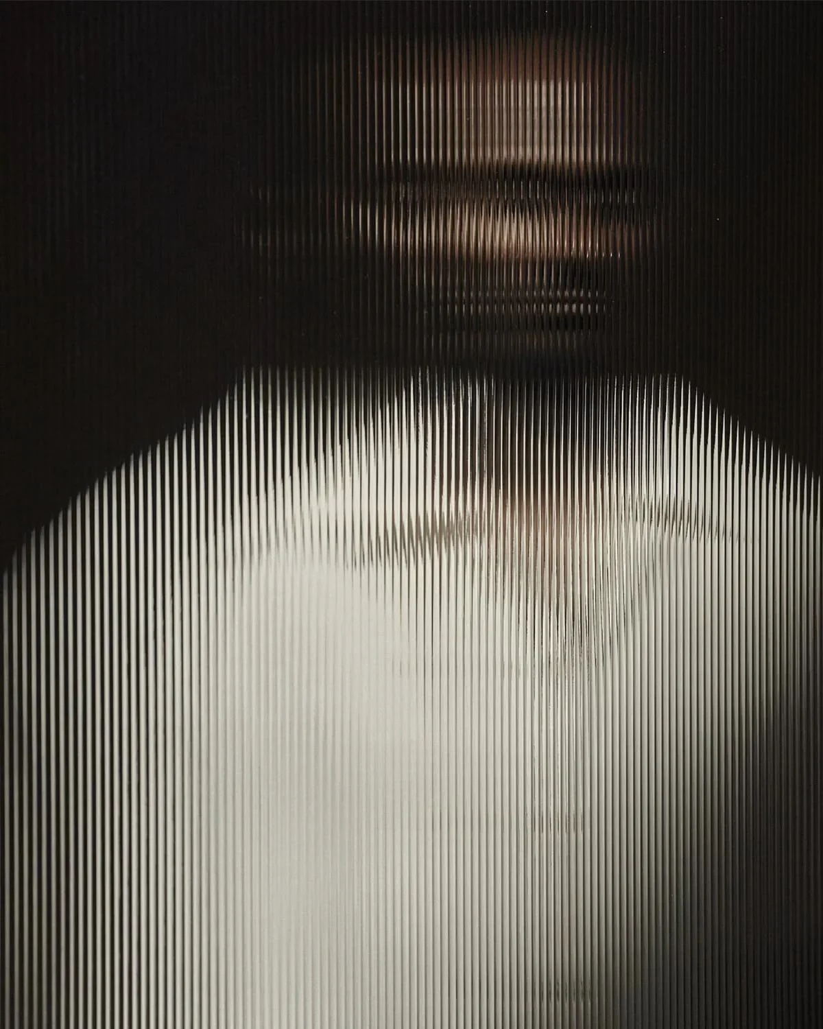 A figure dissolving behind fine vertical striations